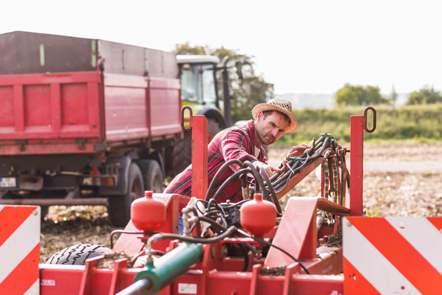 Colaborador realizando inspeção em máquina agrícola.